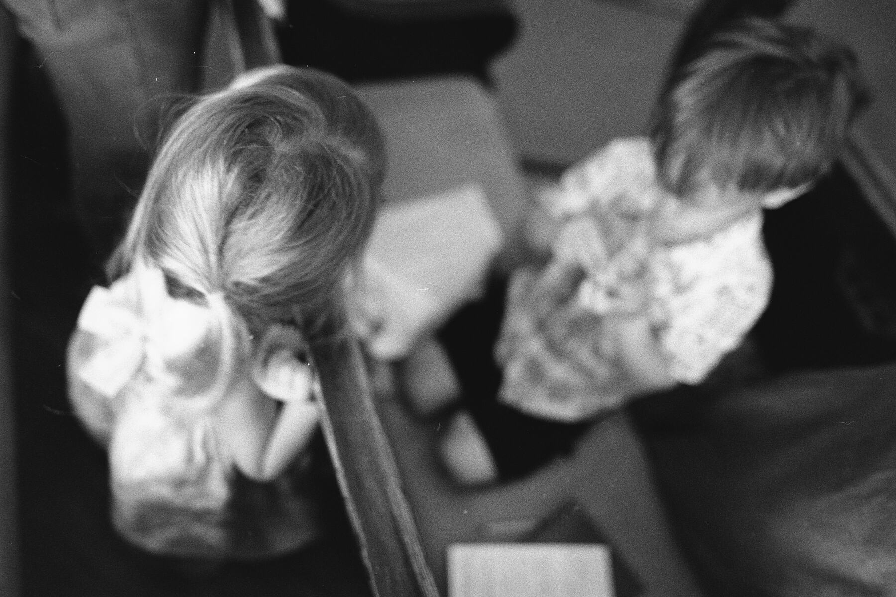 Two young children standing together in a pew during the service.